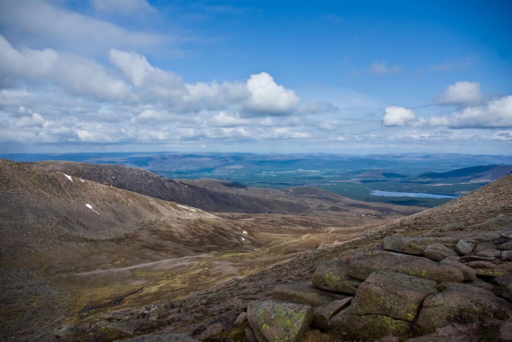 Steniga bergssluttningar med skog och en sjö i fjärran nära Aviemore