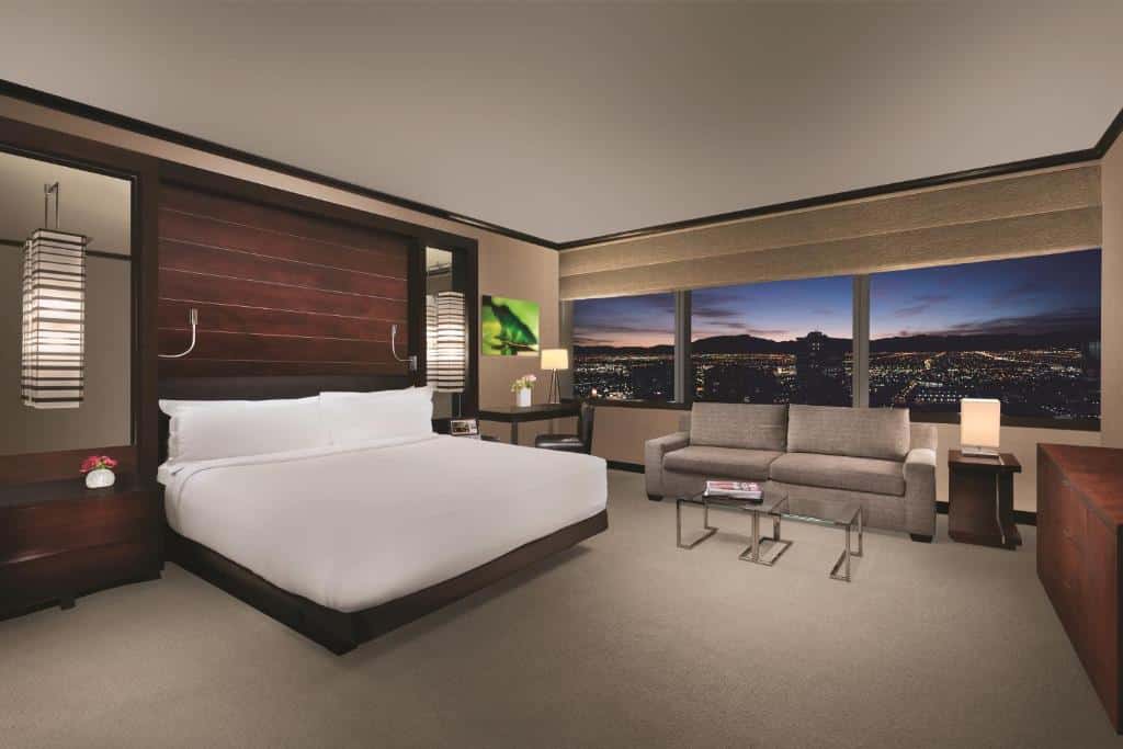 Säng och sittgrupp vid stora fönster i en svit på Vdara Hotel & Spa