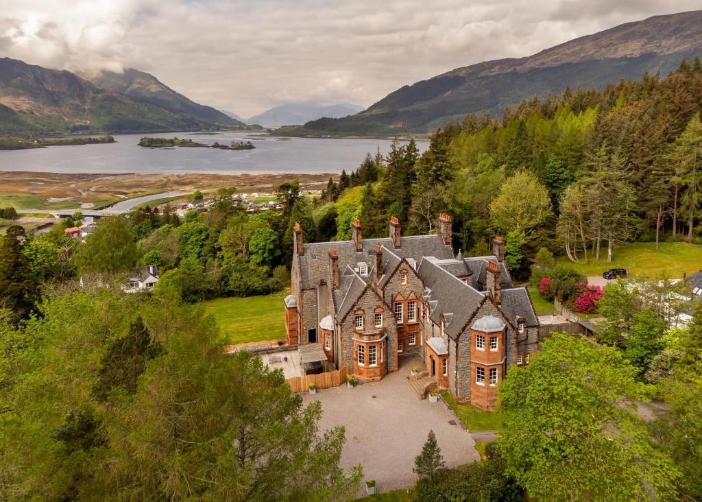 Glencoe House omgivet av träd med en sjö och berg i bakgrunden
