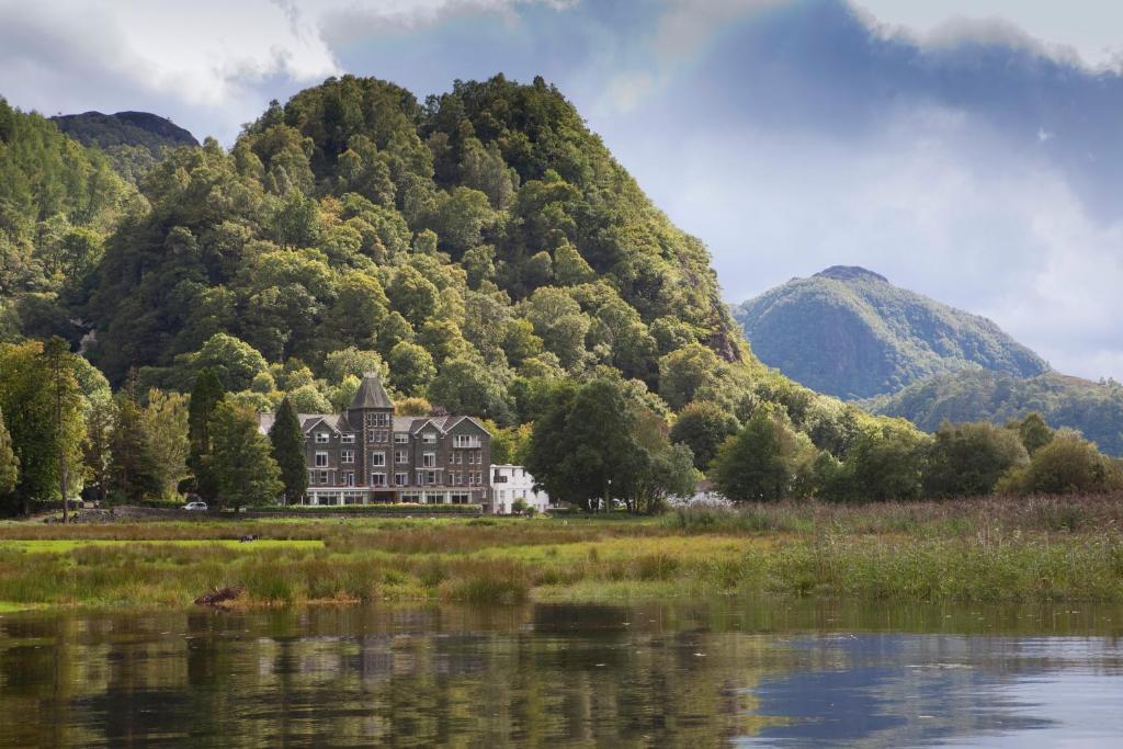 Lodore Falls Hotel speglas i vattnet vid Derwentwater med skog bakom hotellet