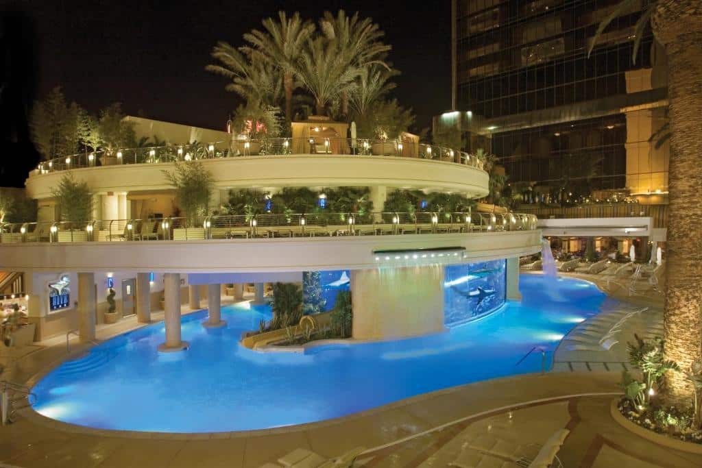 Blått upplyst pool med palmer och terrasser på Golden Nugget på natten