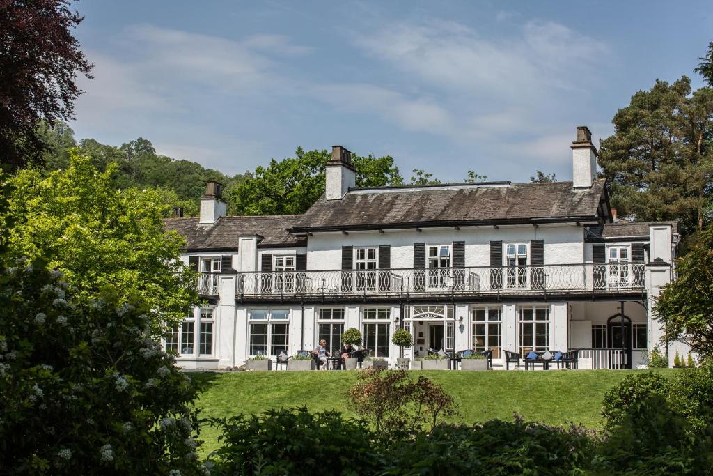 Vit fasad och balkong på Rothay Manor Hotel omgivna av träd i trädgården