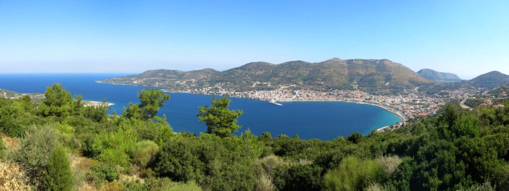 Vid utsikt över en vik på Samos med skogklädda sluttningar och bebyggelse längs kusten