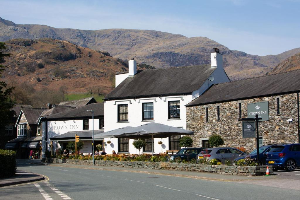 Vit fasad och stenvägg på The Crown Inn intill vägen i Coniston