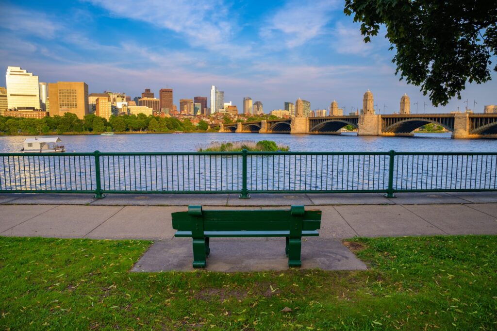 Bänk vid Charles River med Bostons skyline och en bro i bakgrunden