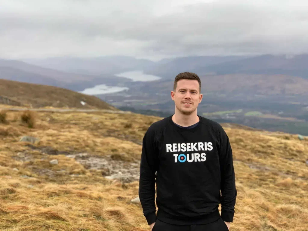 En vandrare på en gräsbevuxen sluttning med berg i fjärran nära Fort William