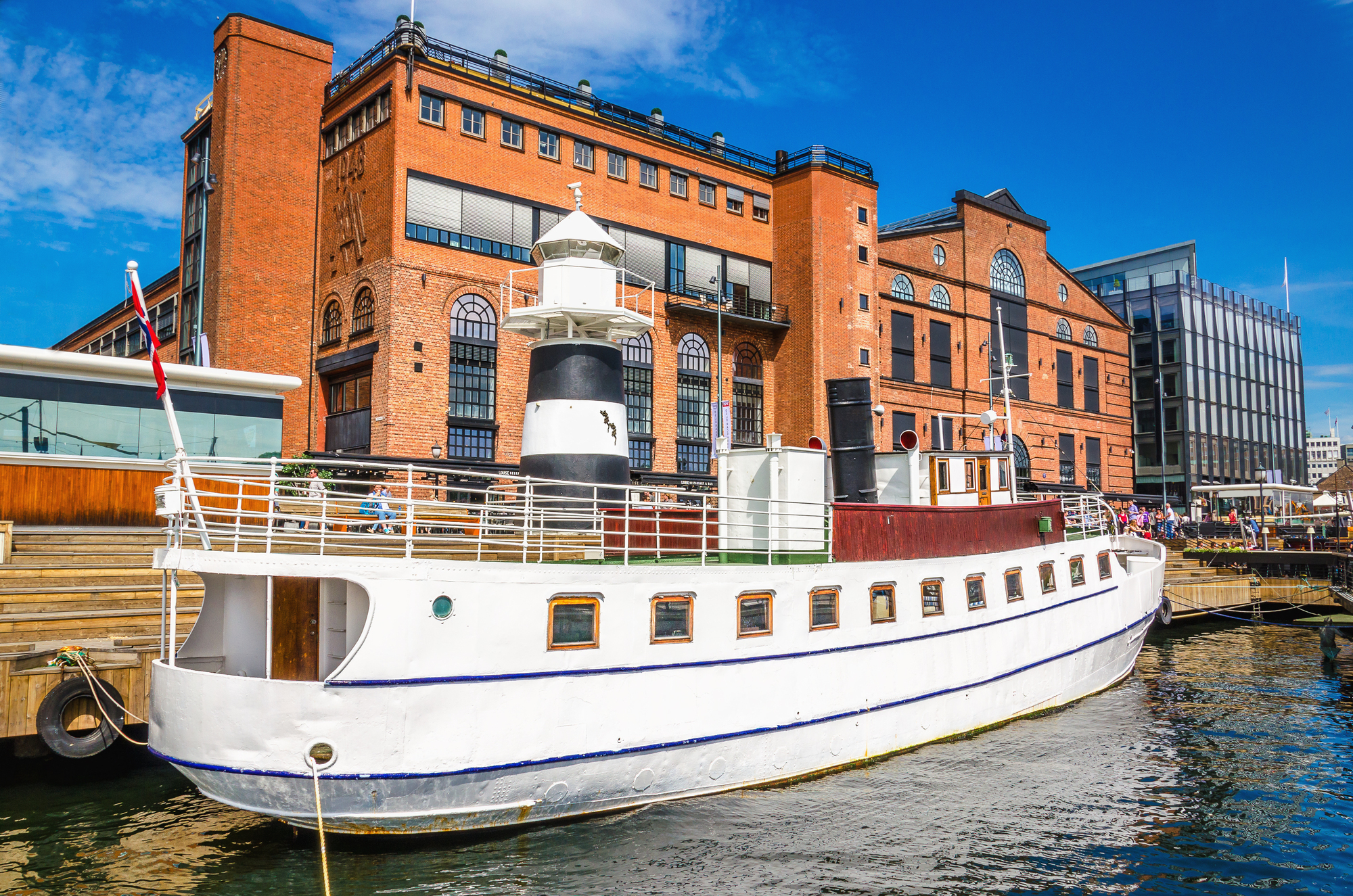 Aker Brygge i Oslo med en vit yacht i hamnen
