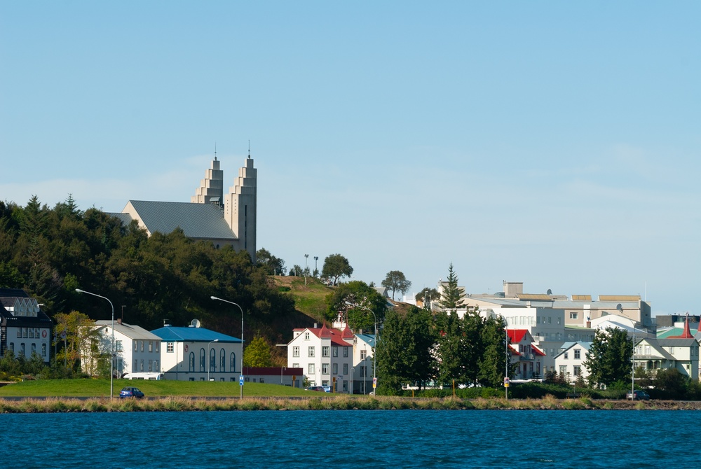 Akureyri sett över fjorden Eyjafjörður med färgglada hus längs vattnet och kyrkan ovanför staden