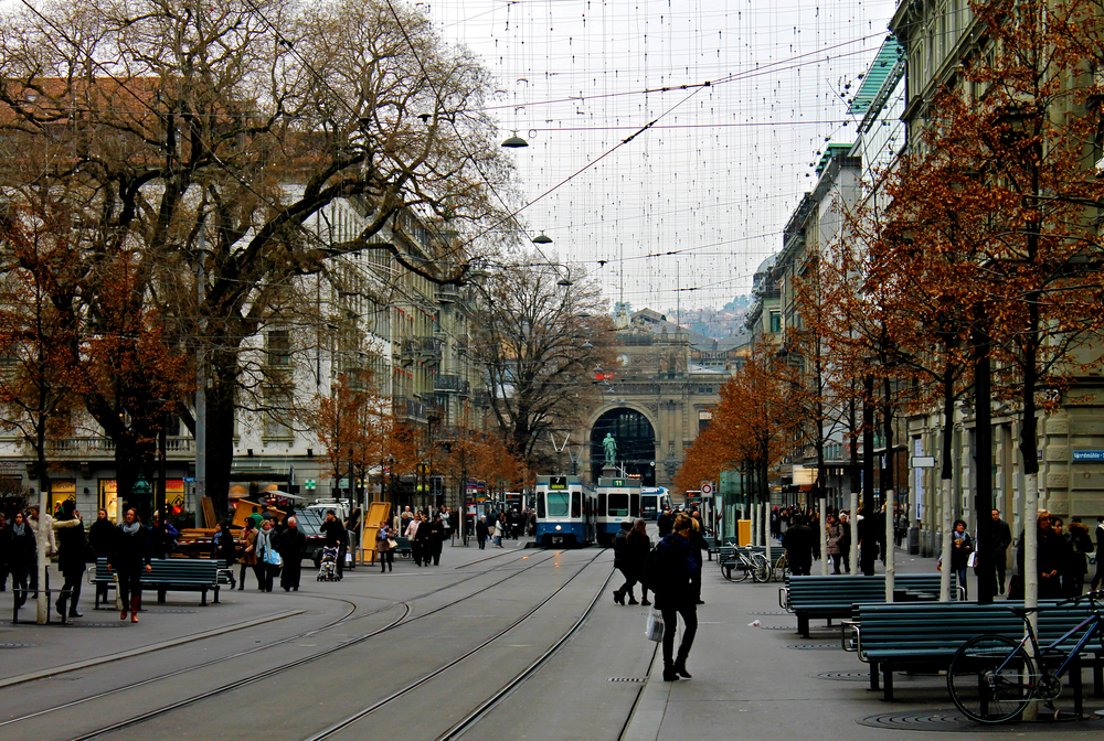 Bahnhofstrasse i Zürich med spårvagnsspår och fotgängare och centralstationen i slutet av gatan
