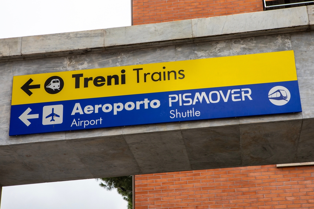 Skyltar på Pisa Centrale mot tågen, flygplatsen och skytteltåget