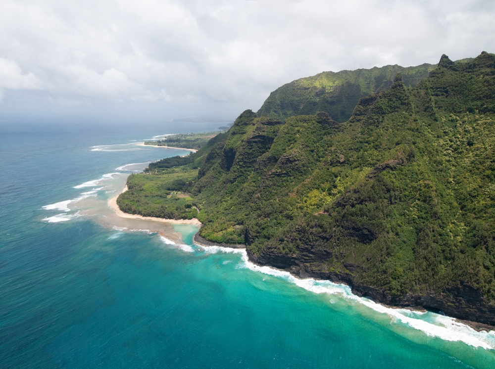 Flygfoto över Na Pali-kusten på Kauai med branta gröna klippor och turkost hav