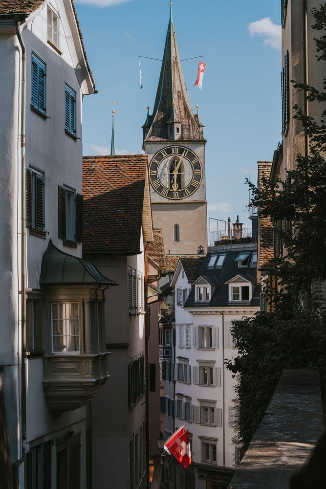 Gata i Niederdorf i Zürich med schweiziska flaggor och St. Peters torn i bakgrunden