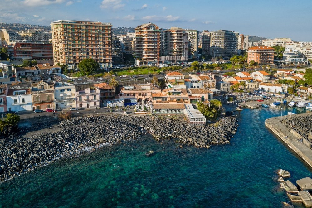 Den lilla hamnen och den svarta lavastranden vid San Giovanni li Cuti i Catania
