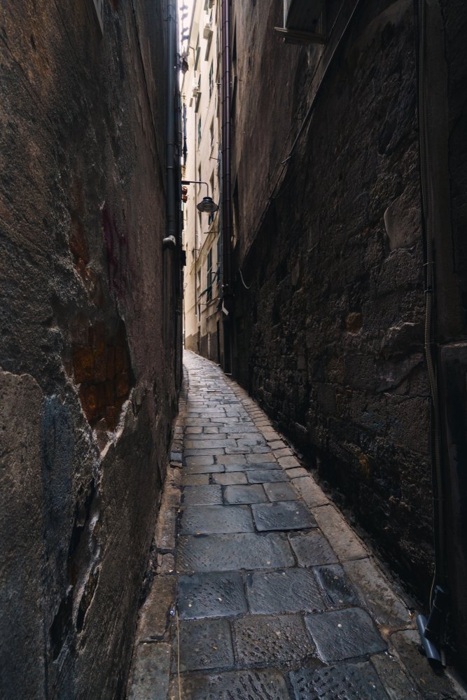 Smal gränd mellan höga hus i Centro Storico i Genua