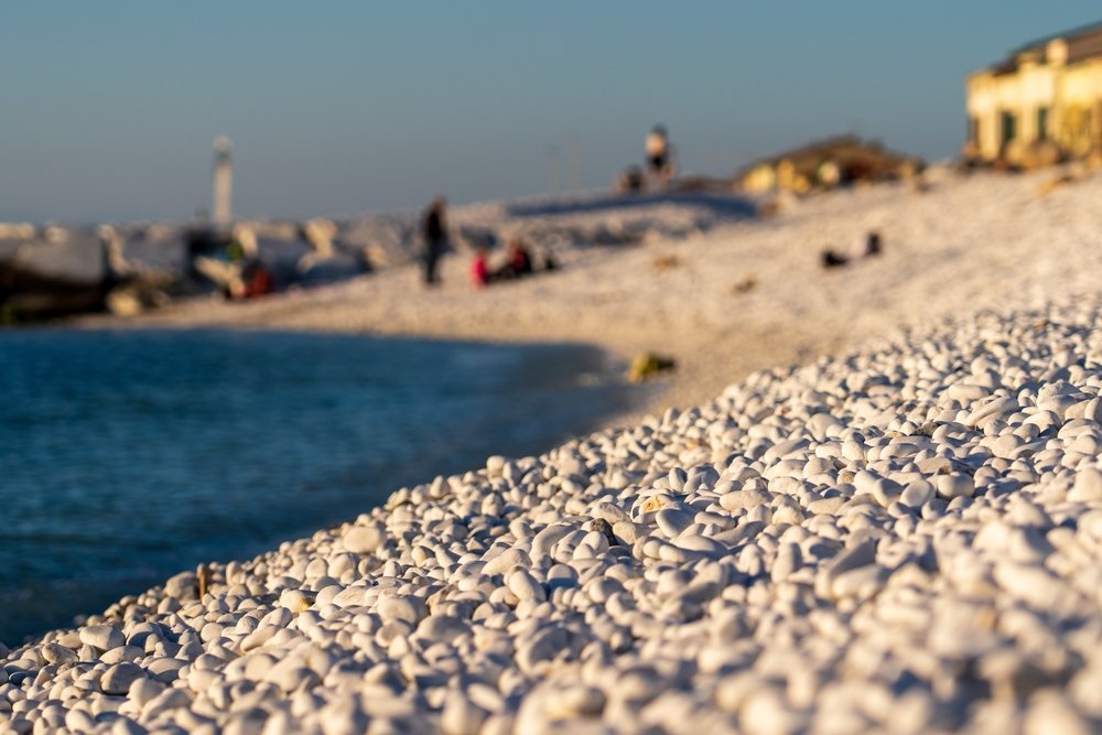 Stranden med vita stenar och vågbrytare i Marina di Pisa