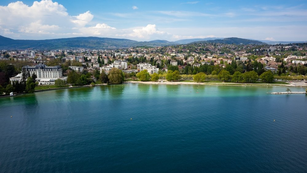 Flygfoto över Annecy och den turkosa sjön Lac d'Annecy med bergen i bakgrunden