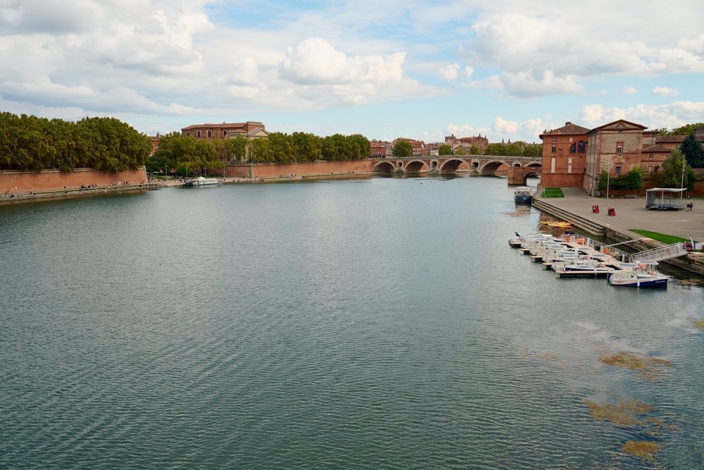 Floden Garonne och bron Pont Neuf i Toulouse med de rosa tegelhusen längs kajen